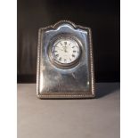 A small silver faced clock. 9cm hight