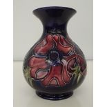 Moorcroft pottery baluster vase with flared neck, tube-lined in the Anemone pattern against a blue