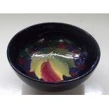 Moorcroft pottery footed bowl tube lined in the leaf and grape pattern against a blue ground ,