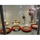 Four framed pot lids; together with two Continental porcelain figures, a cup and saucer and a