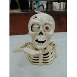 A cast-iron novelty moneybox in the form of a skeleton