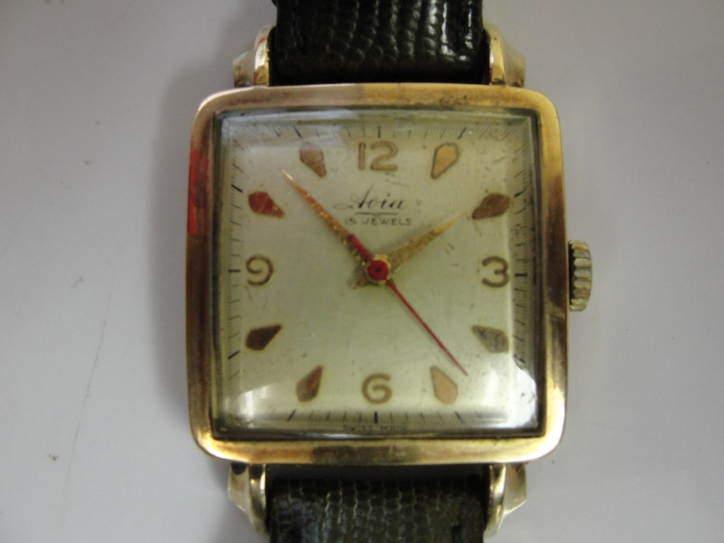 A gold Avia wristwatch on a green leather strap,