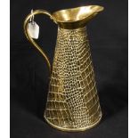 A large copper bottomed brass jug with embossed crocodile skin decoration. Height 33cm