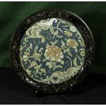 An Oriental hardwood carved frame with silk embroidered panel, 37cm in diameter