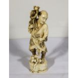 A carved ivory figure of a man with monkey holding branches of apples