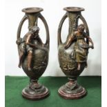 A pair of spelter urns with applied figures on red marble bases