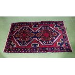 A hand knotted red ground woolen rug, 88cm x 142cm