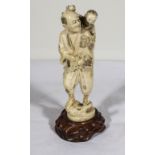 A carved ivory figure of a man carrying a boy on his shoulder