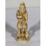 A carved ivory fisherman with spear and fish