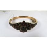 A late 19th century silver gilt hinged bangle, pave set with rose and table cut garnets