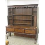 A Georgian Welsh dresser having an open plate rack flanked by inlaid cupboards over drawers on