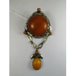 An early 20th century arts and crafts silver brooch set with amber and coral in a styalized