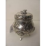 A 19th century continental silver tea caddy with bird form knop over ornate embossed decoration on