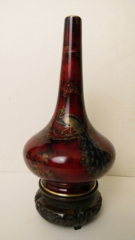 Bernard Moore flambé glazed Peacock vase in mottled blue with gilt highlights, on a carved wooden