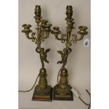 A pair of early 20th century candelabra having three branches over a cherub on square bases, later