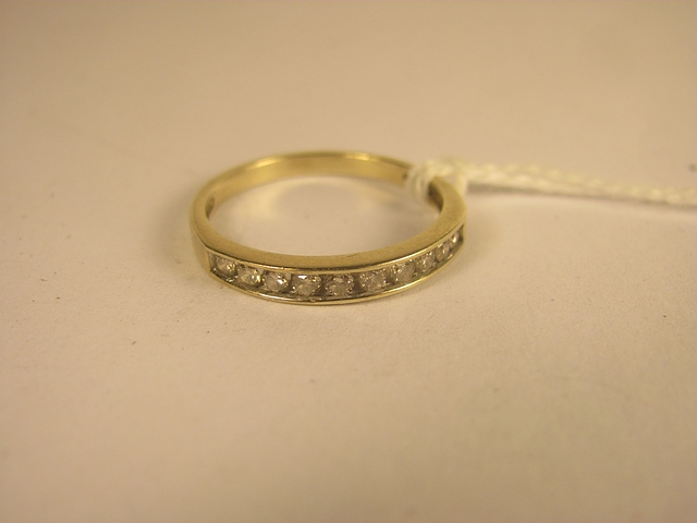 A yellow gold channel set diamond half eternity ring set with brilliant cut diamonds
