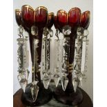 A pair of Victorian ruby glass lustres having gilt highlights and cut glass drops