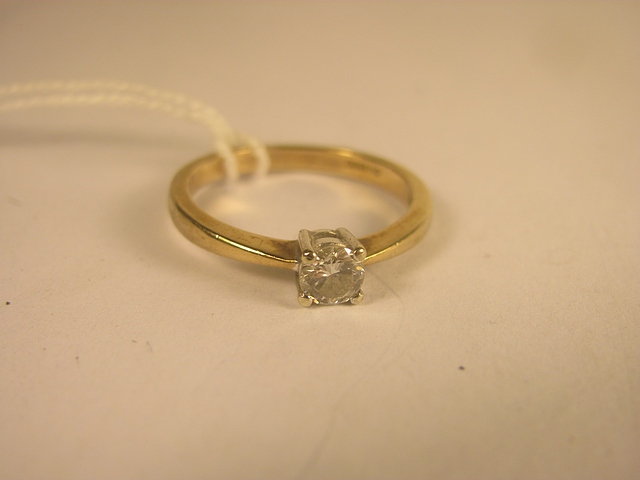 A yellow gold diamond solitaire ring set with a brilliant cut diamond, weighing approximately 0.