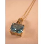 An octagon cut blue topaz and diamond pendant on gold chain