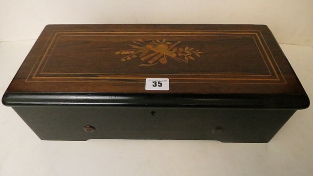 A small early 20th century musical box with a marquetry inlaid lid and playing six airs