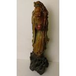 An early 20th century carved soapstone figure of a wise man standing on a rocky base, 18" high