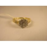 A contemporary 18ct yellow gold brilliant cut diamond cluster ring with diamond set shoulders