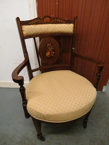 An Edwardian inlaid mahogany salon chair with upholstered feet on tapering front legs and castors