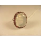 A large white metal oval cabochon moonstone and ruby cluster ring