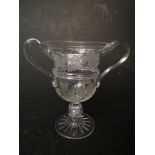 A 19th century etched glass, twin handled loving cup with a coin set with in the stem