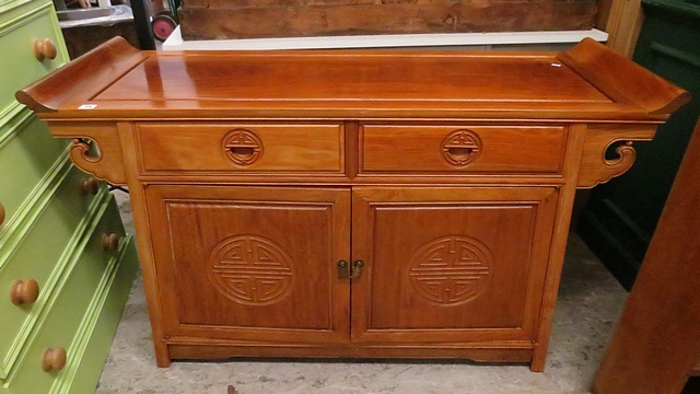 A Chinese hardwood side cabinet with two drawers over twin cupboard doors, with carved