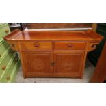 A Chinese hardwood side cabinet with two drawers over twin cupboard doors, with carved