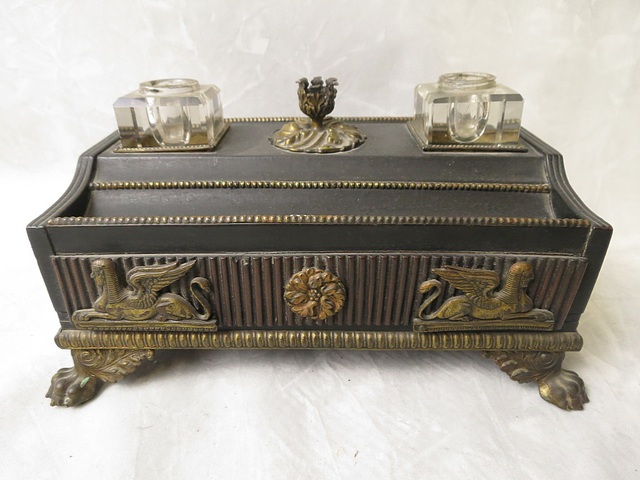 A Regency style ebonized desk ink stand with ormolu taper stick holder, flanked by two glass ink