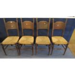 Four early 20th century oak arts and crafts chairs having solid backs over rush seats on circular