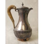 A Georgian silver hot milk jug having a wicker handle and leaded body, London 1760