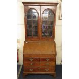 An 18th century George II walnut bureau bookcase having mahogany cross banding, arch top doors