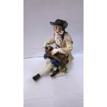 A 19th century Meissen porcelain figure of a man smoking a pipe and playing the Hurdy-Gurdy, cross