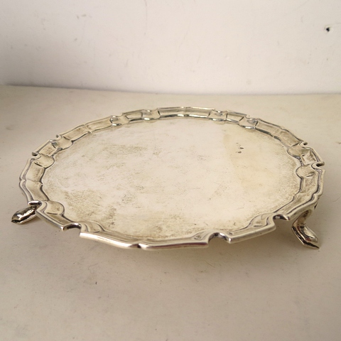 A Goldsmiths and Silversmiths Company silver card tray having a shaped rim over raised feet,