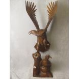 A large contemporary carved softwood sculpture of an eagle taking flight, on a rocky base, 42 high