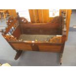 A 19th century continental rocking cradle having carved head and foot board with turned spindles