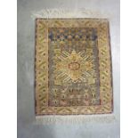 A small Persian bordered silk Rug with central snowflake design on a blue ground, 34 x 26in,