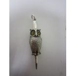 A white metal Figure of an owl in the form of a pencil