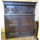 An antique oak Court Cupboard having a small pair of cupboard doors flanking a carved roundel