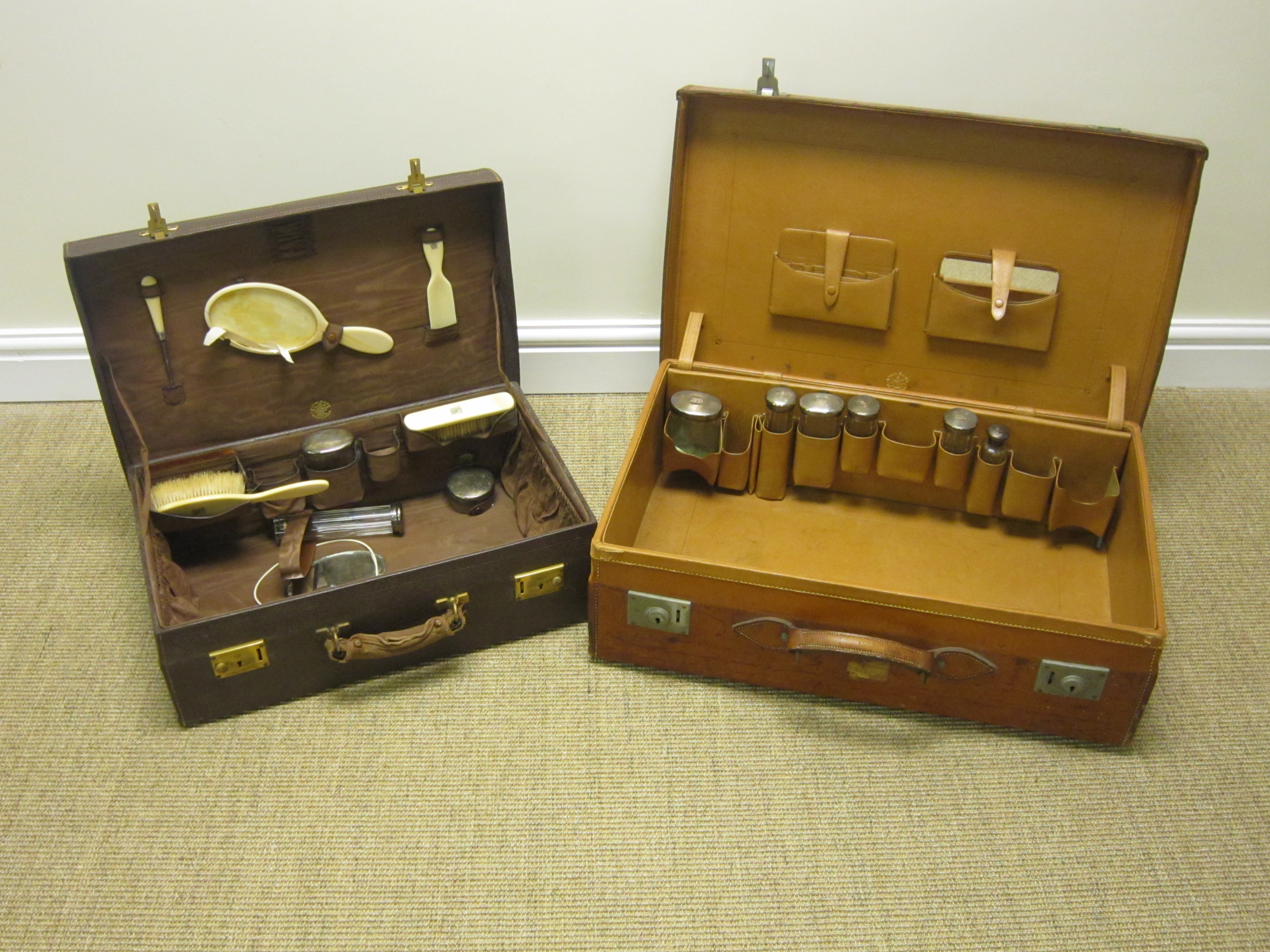 Two leather Travelling Cases, both with part sets of silver mounted fittings