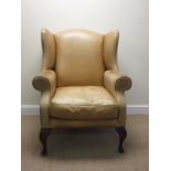 A faded brown leather upholstered wing back Armchair on mahogany cabriole supports