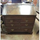 An antique oak Bureau with fitted interior and well above two short and two long drawers on