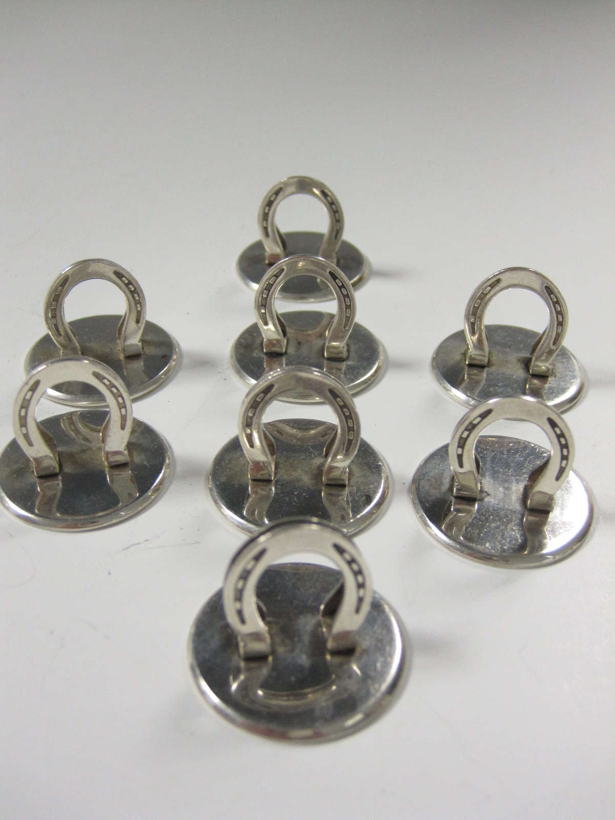 Eight silver Menu Holders in the form of horse shoes on circular bases, stamped Birmingham T&S