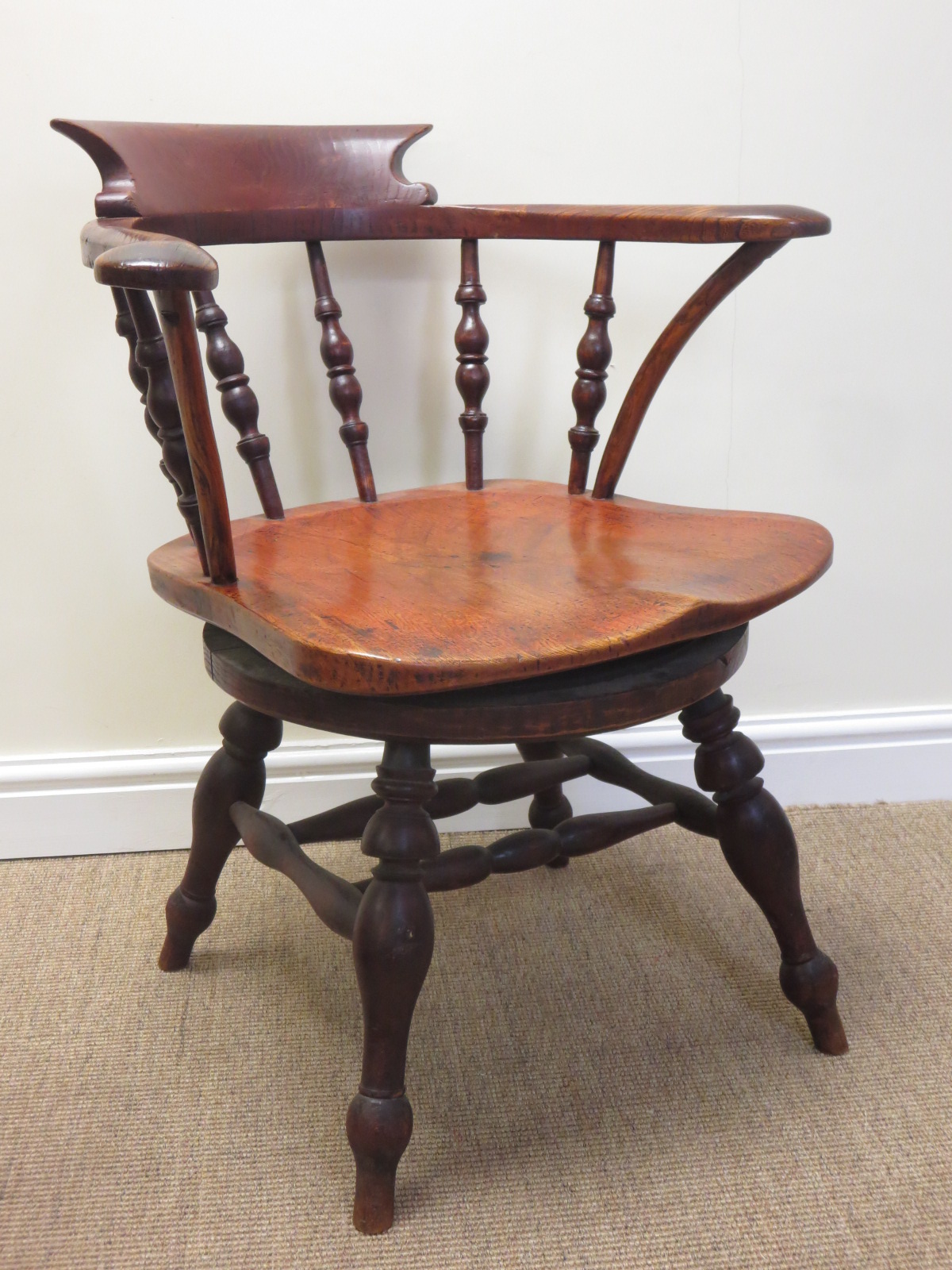 An antique elm revolving Captain’s Chair with turned spindle back on four turned legs