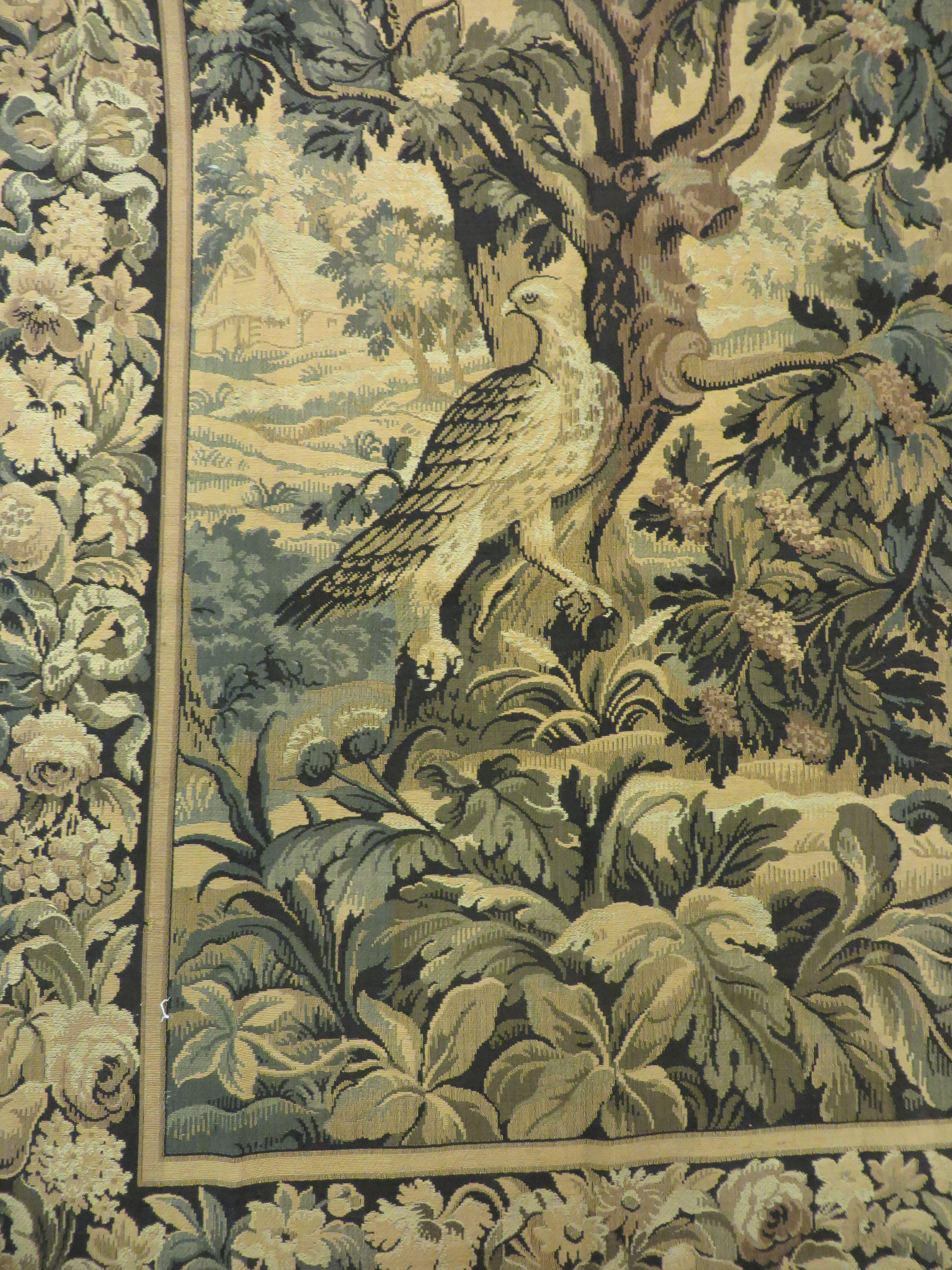 A French made 17th Century style verdure Tapestry with central bird and fruit and flower border.