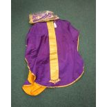 A purple satin and metallic gold Chasuble with raised IHS Christogram, lined in orange, with