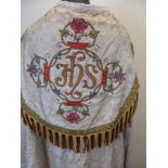 A cream brocade Cope, the hood embroidered with polychrome flowers and IHS. Edged with braid and